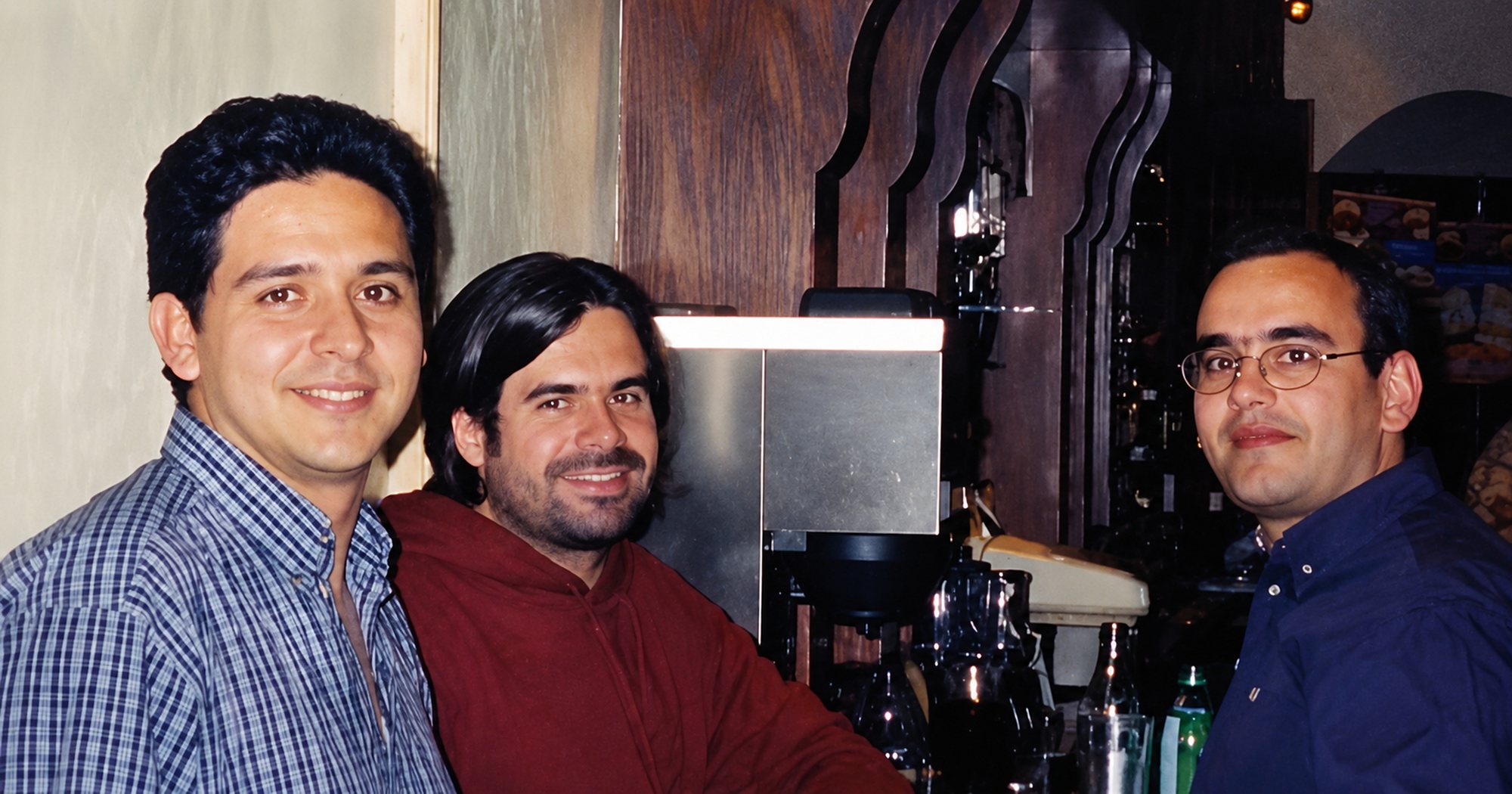 The three authors standing side by side and smiling at the camera in an older photograph.